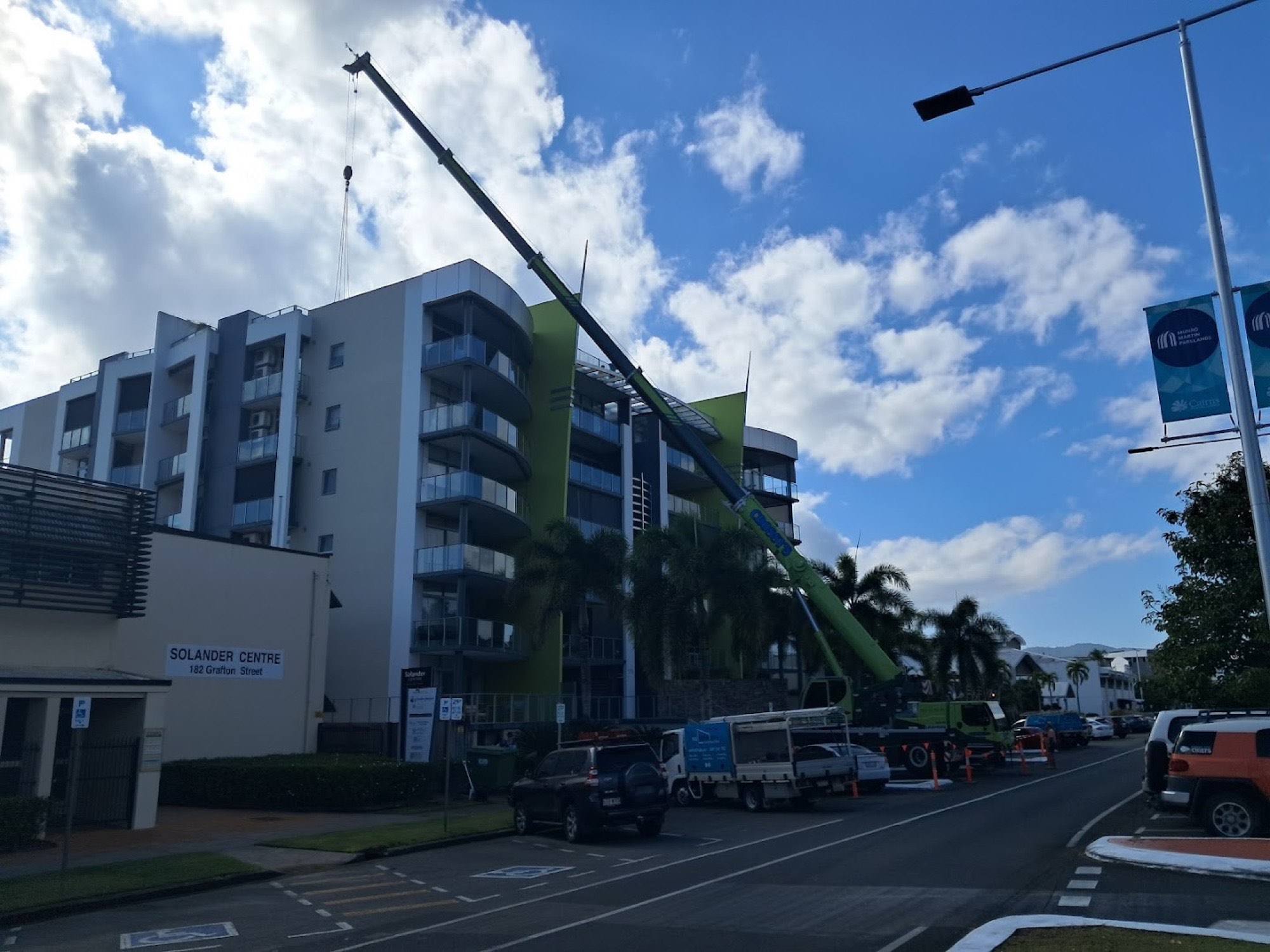 A multi-storey building under construction beside palms on a Cairns street