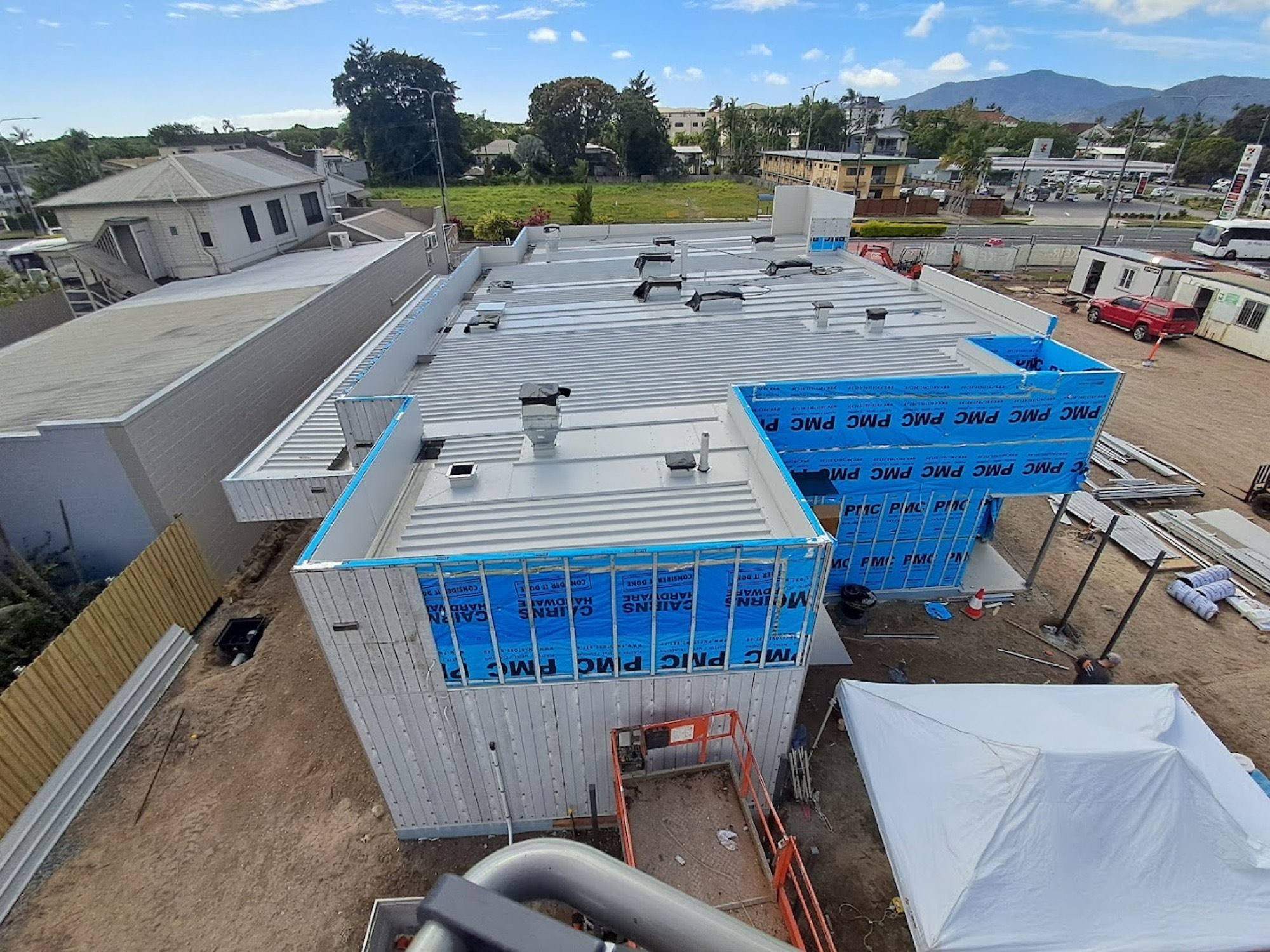 A commercial building under construction seen from the roof, with hills behind