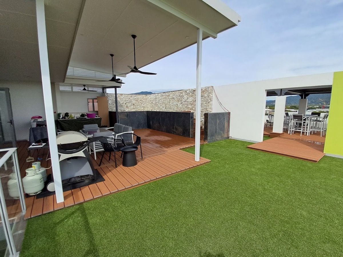 An alfresco area with a hardwood deck, ceiling fans and turf