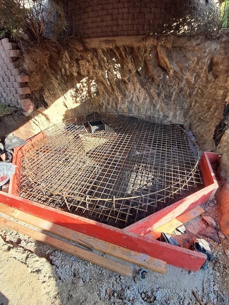 A steel reinforcing cage set inside timber formwork in an excavated pit