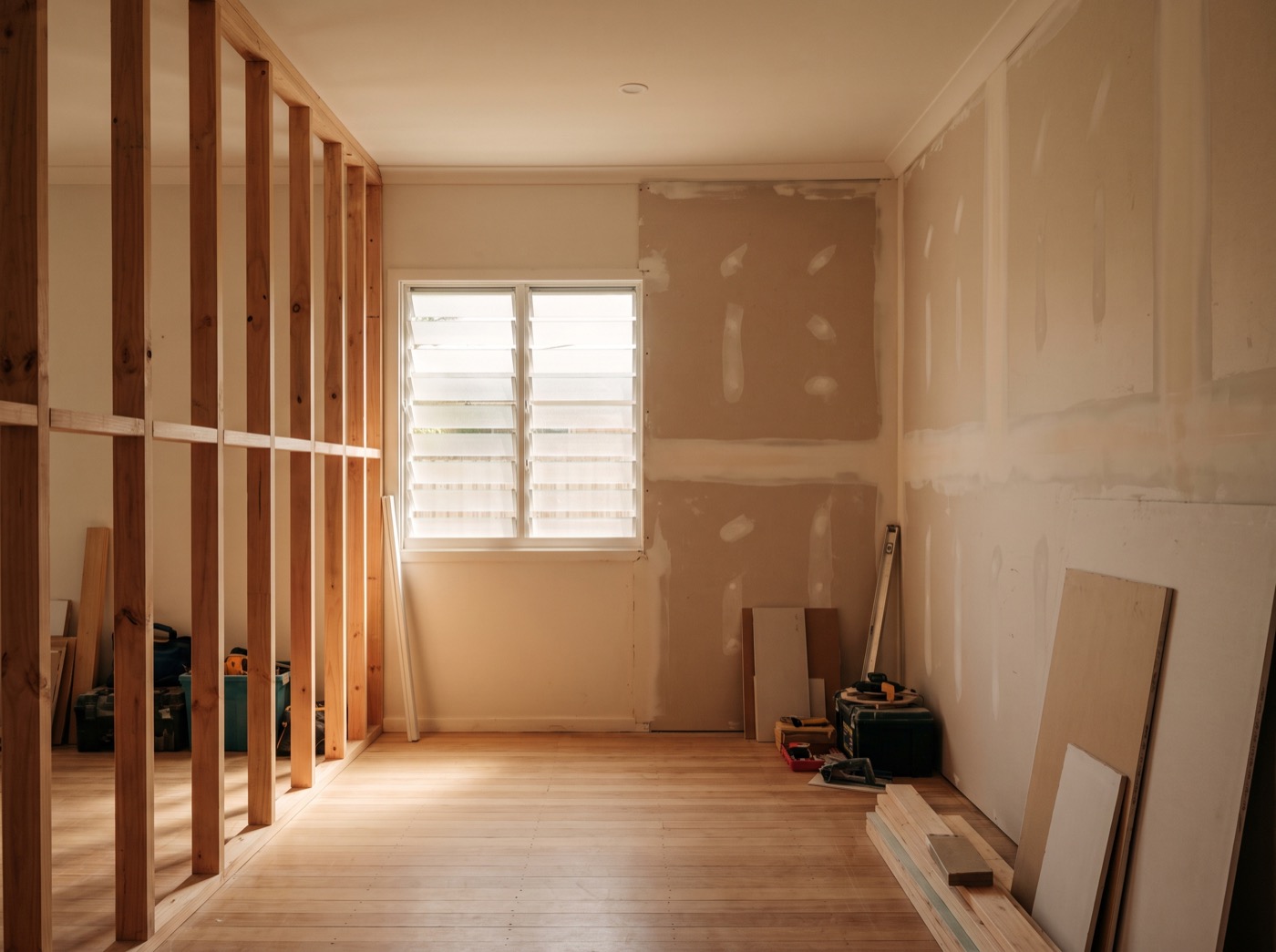 A room mid-renovation with a new timber stud wall on one side and fresh plasterboard on the other