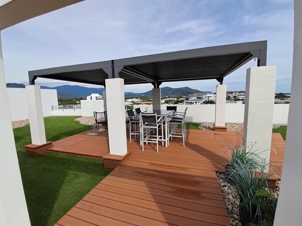 A rooftop entertaining area with a hardwood deck and a louvred pergola