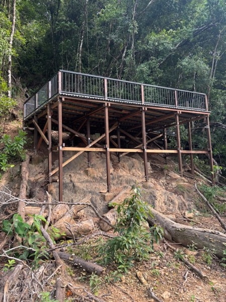 An elevated timber viewing deck built on steel posts in rainforest