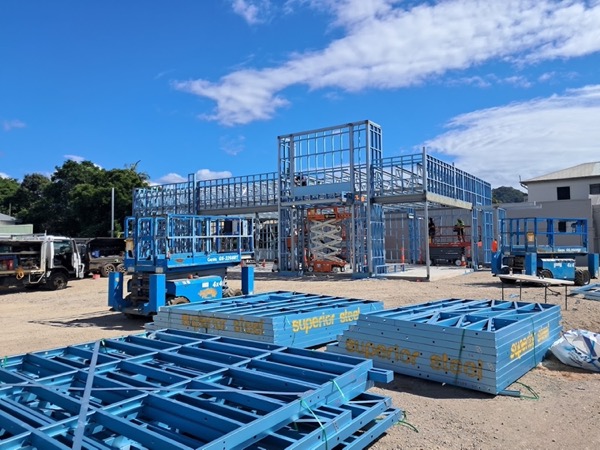 Steel floor frames laid out on a building site with hills behind