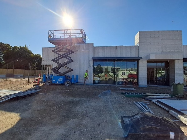 The front of a commercial building being clad, with a scissor lift on the forecourt