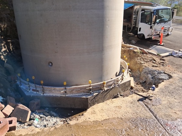 The base of a large concrete tank with formwork and a truck on the site